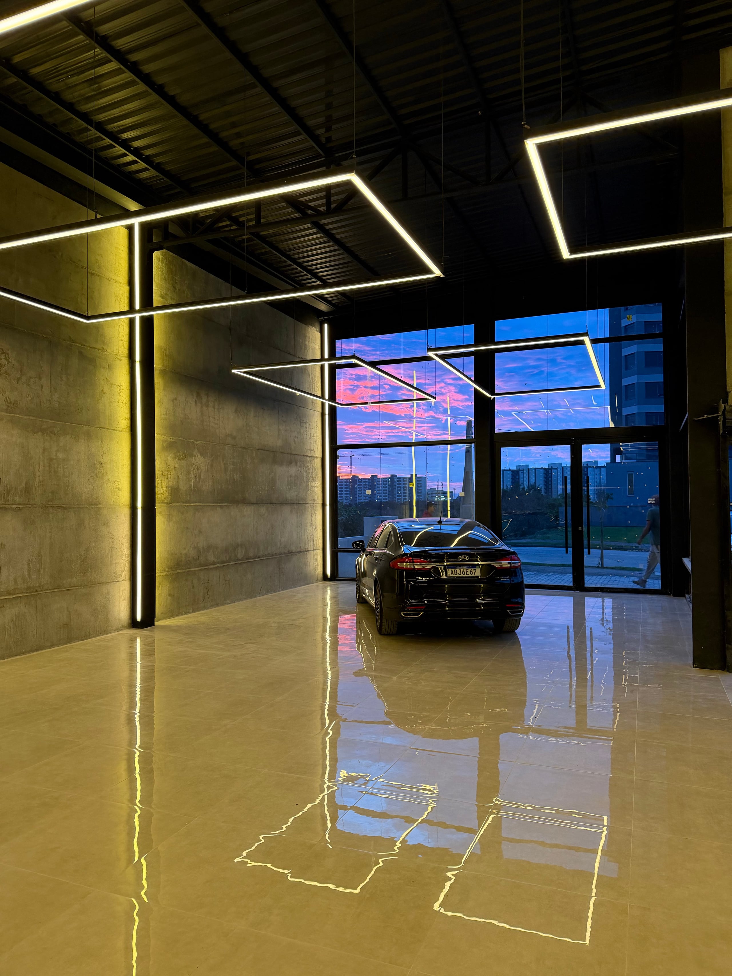 Interior do UNA 65 com concreto aparente, iluminação geométrica e fachada envidraçada