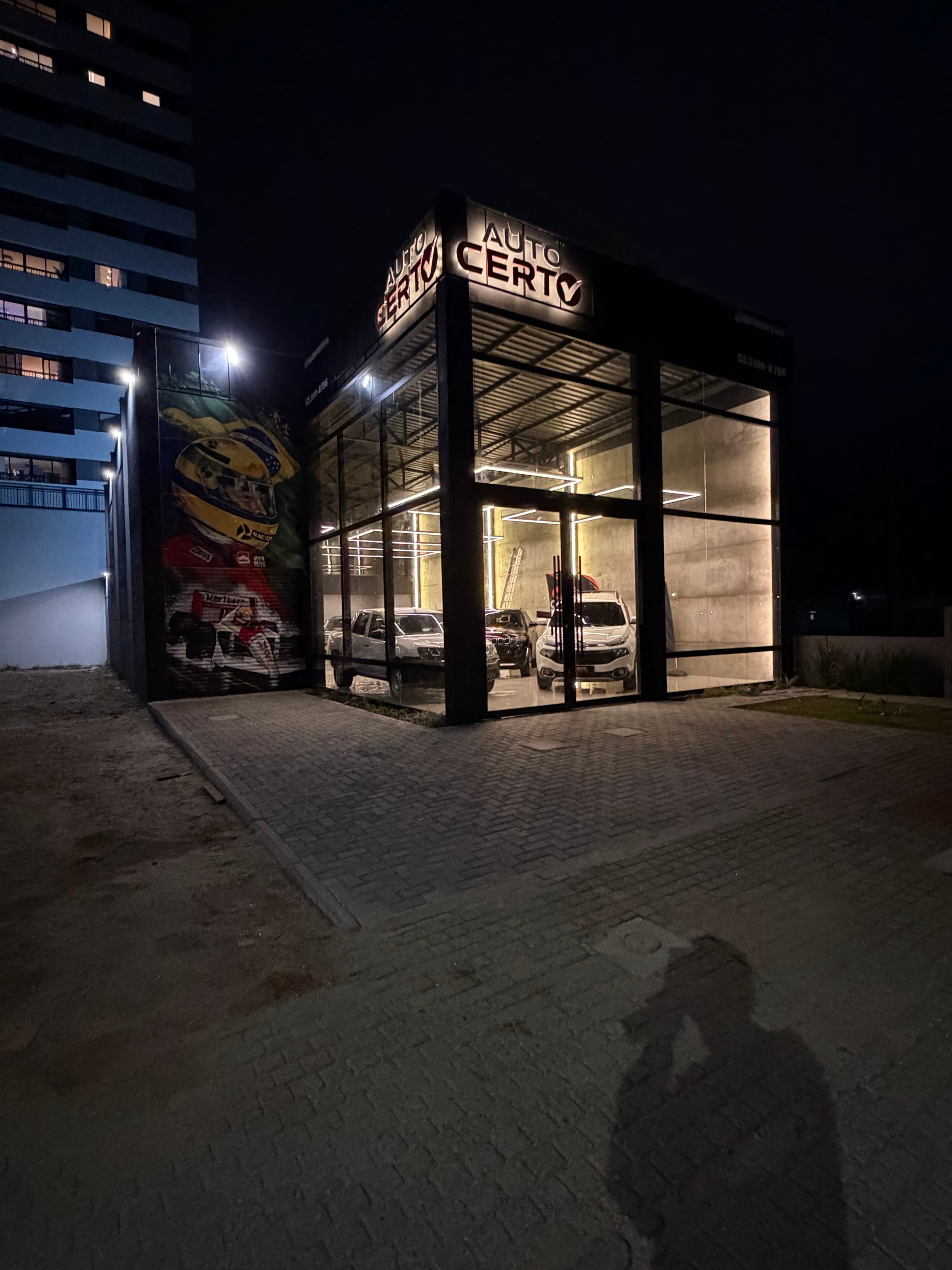 Fachada envidraçada do UNA 65 à noite, com iluminação interna quente